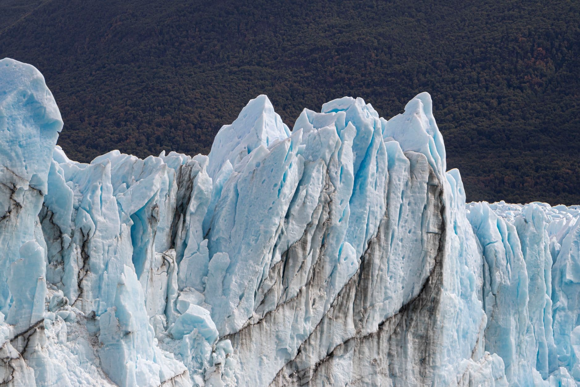Stunning ice formations of a glacier against a mountainous backdrop on a cold winter day.