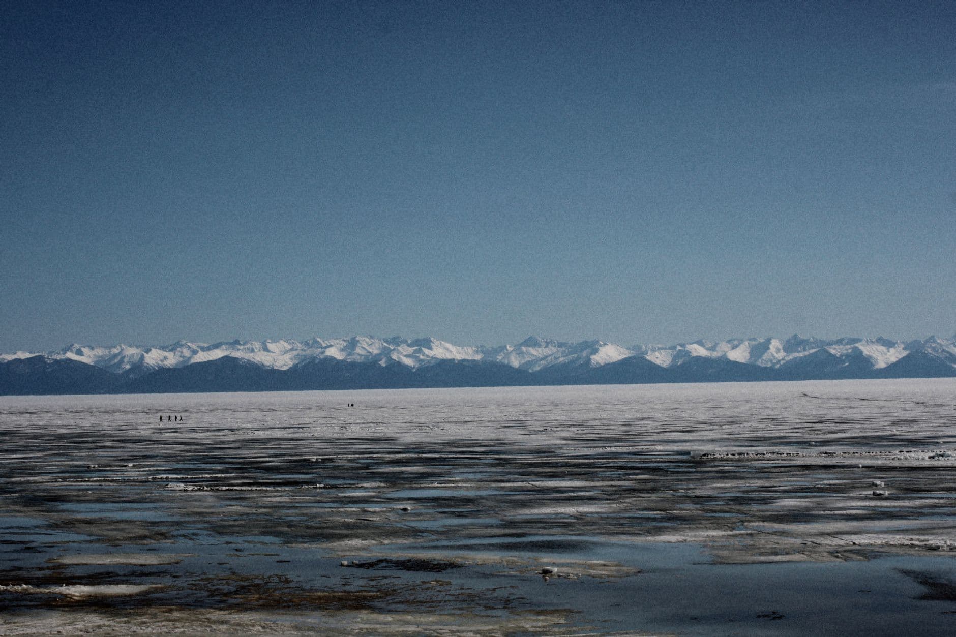 Expansive view of frozen Lake Baikal with distant snowy mountains in Russia.